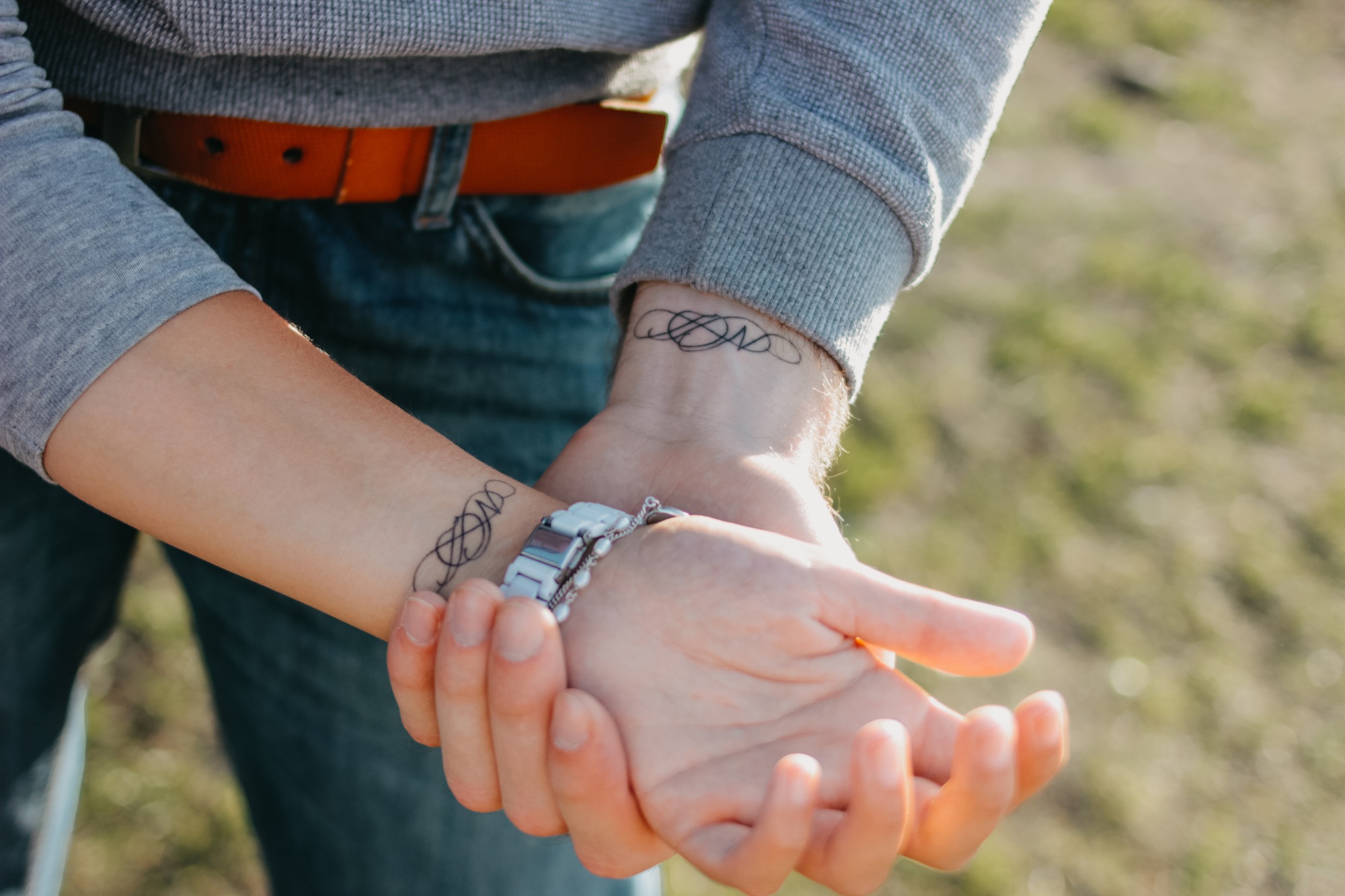 A couple in love holding hand in hand. Paired tattoo initials on the arms