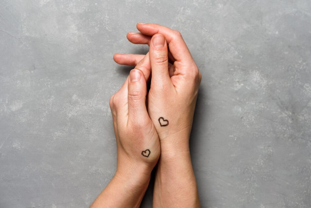 Hands with hearts tattoo on gray