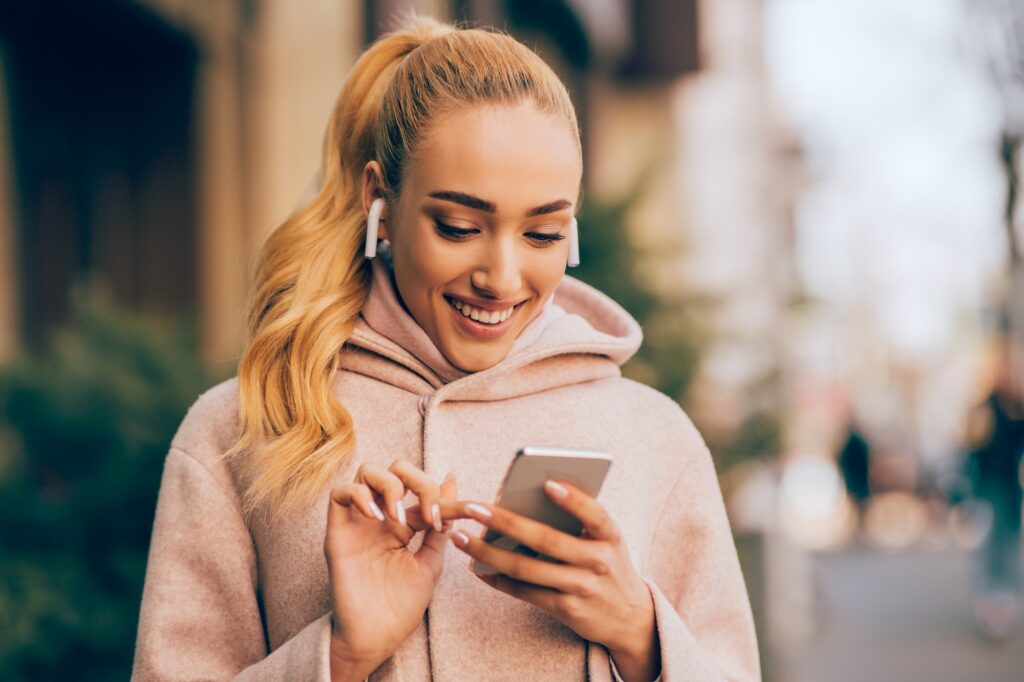 Happy woman texting outdoors on city street