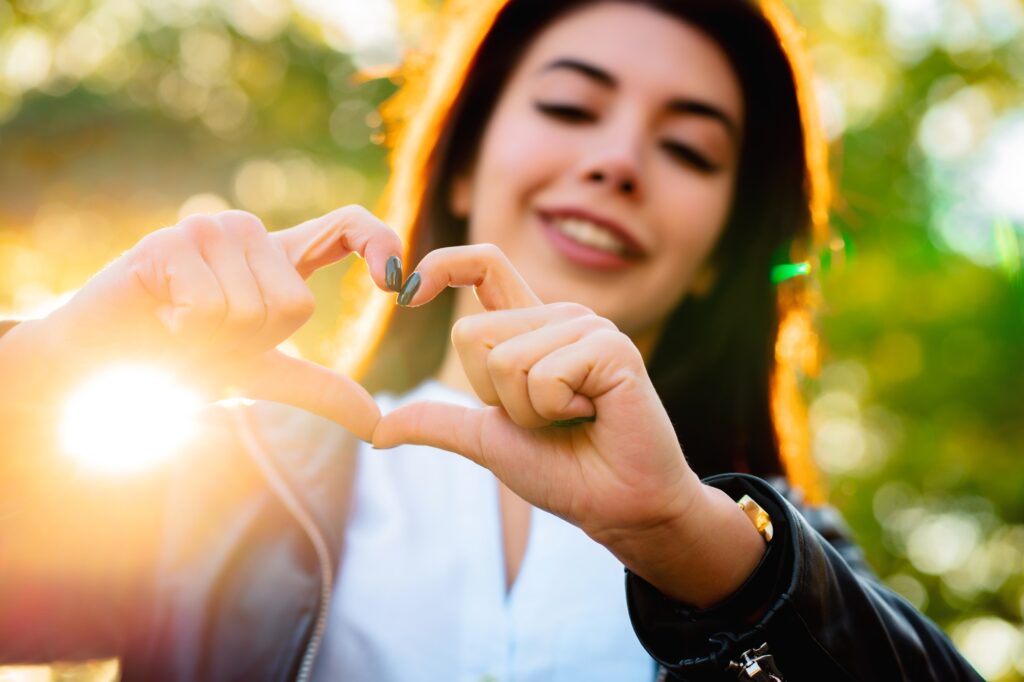 Young beautiful woman showing gesture of LOVE and smiling to camera